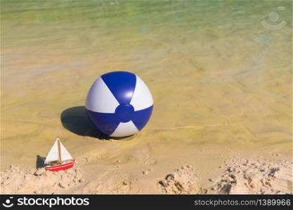 Toy boat and Inflatable blue and white beach ball floating on water