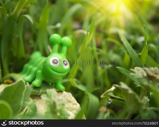 Toy caterpillar in grass. Conceptual scene.
