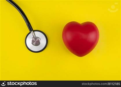 Toy heart and a stethoscope on a yellow background. Top view. Concept healthcare. Cardiology - care of the heart. cardiology, heart care