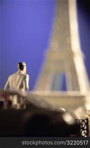 Toy Man Looking at Toy Eiffel Tower