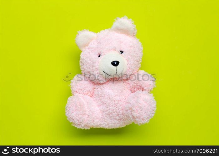 Toy pink bear on green background. Copy space
