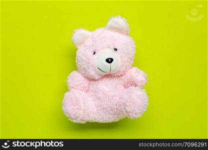 Toy pink bear on green background. Copy space