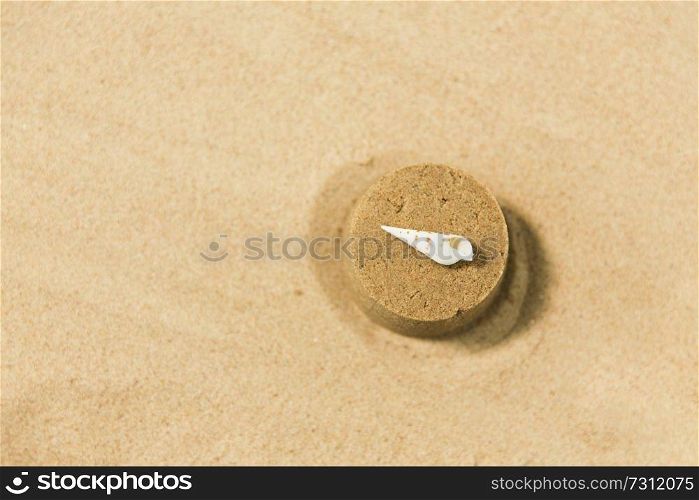 toys, childhood and vacation concept - sand shape made by toy mold with shell on top on summer beach. sand shape made by mold with shell on summer beach
