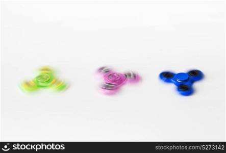 toys, entertainment and motion - three spinning fidget spinners on white background. three spinning fidget spinners on white background