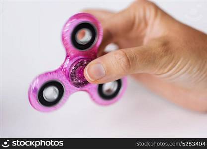 toys, entertainment and people - close up of hand playing with glittering spinning fidget spinner. close up of hand playing with fidget spinner