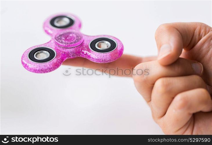 toys, entertainment and people - close up of hand playing with pink glittering fidget spinner and doing finger transfer trick. close up of hand playing with fidget spinner