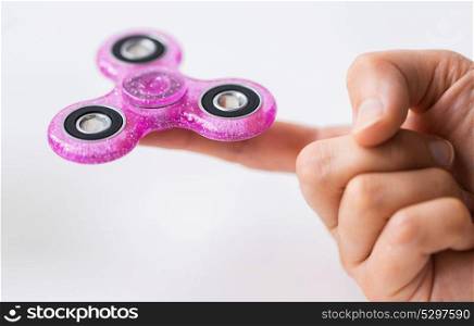 toys, entertainment and people - close up of hand playing with pink glittering fidget spinner and doing finger transfer trick. close up of hand playing with fidget spinner