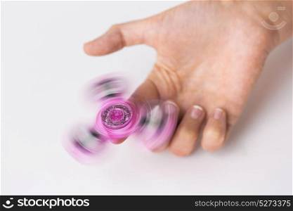 toys, entertainment and people - close up of hand playing with spinning fidget spinner and doing finger transfer trick. close up of hand playing with fidget spinner