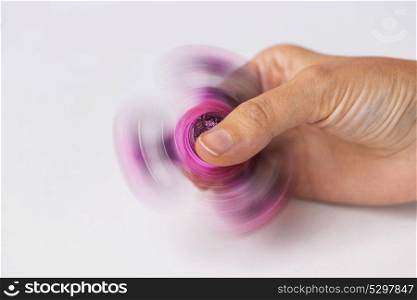toys, entertainment and people - close up of hand playing with spinning fidget spinner. close up of hand playing with fidget spinner
