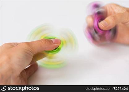 toys, entertainment and people - close up of hands playing with spinning fidget spinners. close up of hands playing with fidget spinners