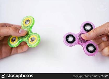 toys, entertainment and people - close up of two hands playing with glittering fidget spinners. close up of two hands playing with fidget spinners