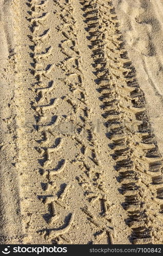 Traces of different car tires on the sand of the sea beach. Close up