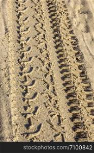 Traces of different car tires on the sand of the sea beach. Close up