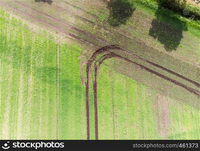 track of a tractor on a field which has made a turn when reaching the field boundary, abstract effect by vertical aerial view, to be used as background, made with drone