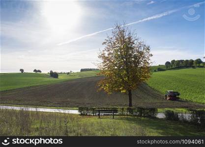tractor and harrow on field in dutch province of south limburg on sunny day in the fall