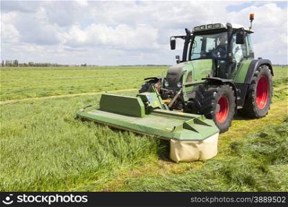 tractor and mower in green meadow in the netherlands on sunny day