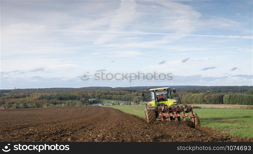 tractor and plow under blue autumn sky on field in luxembourgh