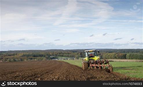 tractor and plow under blue autumn sky on field in luxembourgh