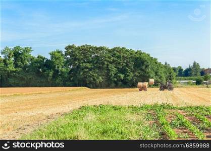 Tractor and trailer with hay bales in rural landscape