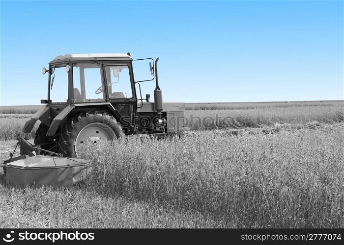 Tractor in a field, agricultural scene in summer. Black and white with a blue sky.