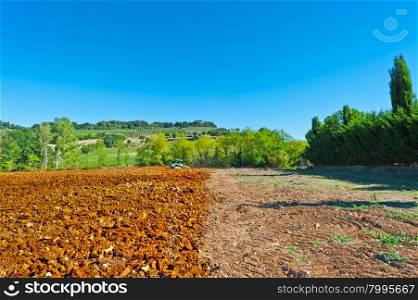 Tractor Plowing Field on a Background of Vineyards in Tuscany, Italy