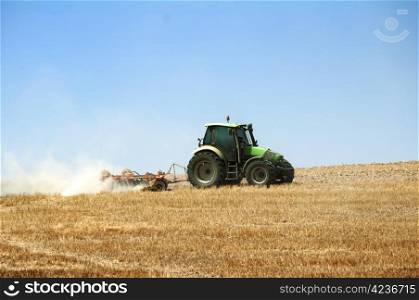 Tractor plowing field on blue sky background.