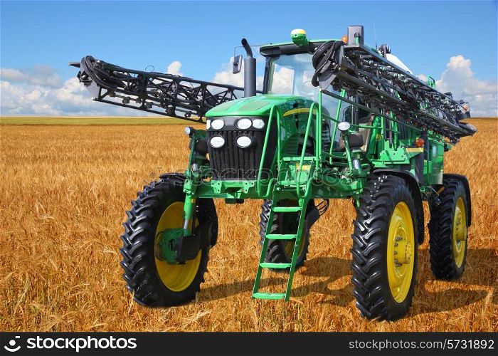 tractor sprayer harvester on a wheat field with a blue sky