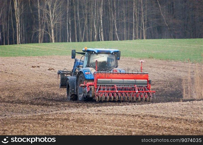 Tractor with a grain seeder in the field, spring view