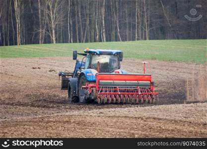 Tractor with a grain seeder in the field, spring view