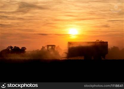 tractor with corn trailer in sunset