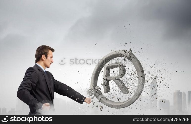 Trademark. Angry businessman crashing stone trademark with karate punch