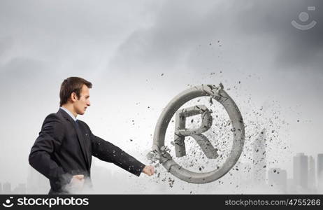 Trademark. Angry businessman crashing stone trademark with karate punch