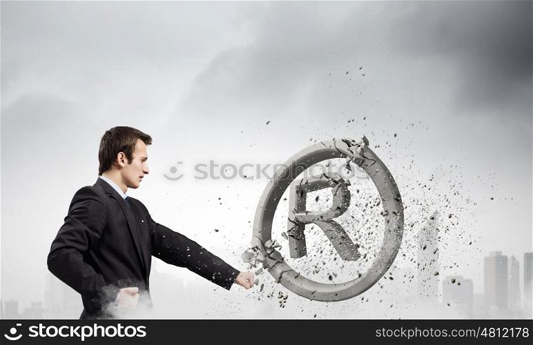 Trademark. Angry businessman crashing stone trademark with karate punch