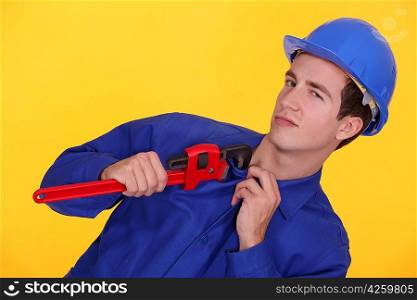 Tradesman&acute;s uniform stuck in the jaw of a pipe wrench