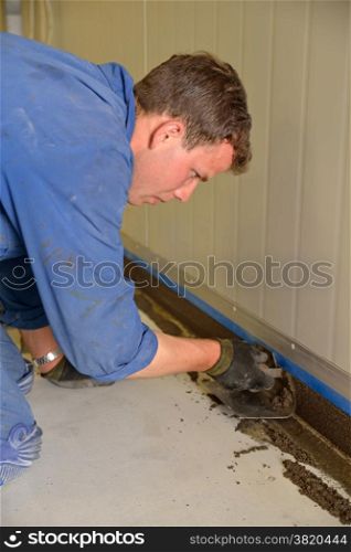 tradesman applying epoxy product to coving around the floor of an industrial building