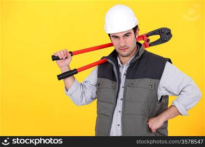 Tradesman carrying a pair of large clippers on his shoulder