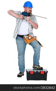 Tradesman holding a drill with a long bit