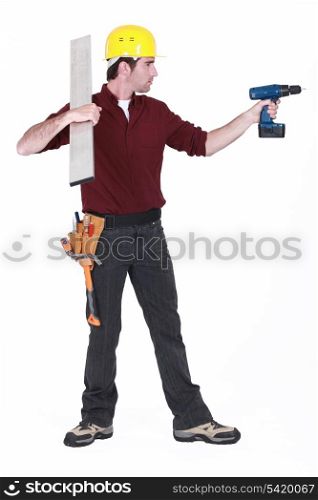 Tradesman holding a girder and a power tool