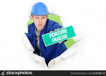 Tradesman holding a &rsquo;Wet Paint&rsquo; sign