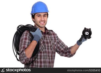 Tradesman holding electric cabling and a piggy bank