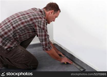 Tradesman laying down linoleum flooring