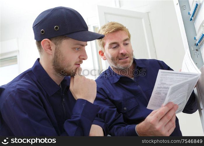 tradesman looking at instruction book by circuit breaker box