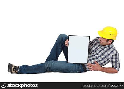 Tradesman lying on the floor and holding a whiteboard