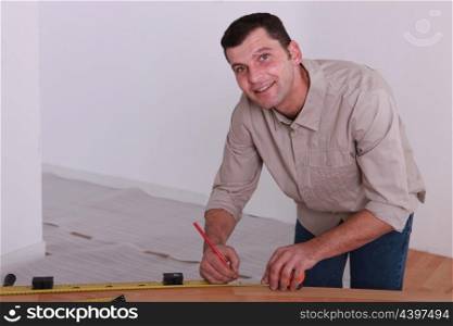 Tradesman marking a measurement on a wooden plank