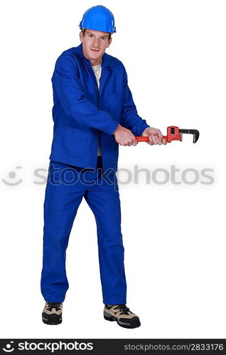 Tradesman trying to pull an invisible object using a pipe wrench