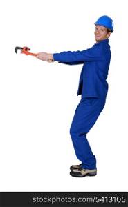 Tradesman using a pipe wrench to drag an invisible object