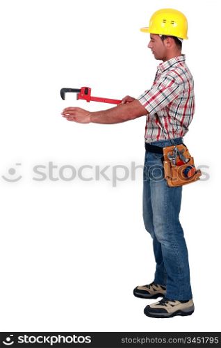 Tradesman using a pipe wrench to help drag and place an object