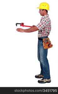 Tradesman using a pipe wrench to help drag and place an object