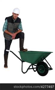 Tradesman with his foot propped on a wheelbarrow