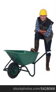 Tradesman with his foot propped on a wheelbarrow